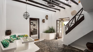 A spacious interior with a high ceiling, exposed wooden beams, a white wall, and a stone floor. - Las Pergolas Villa Rural - Apartamento Yaiza (Tías)