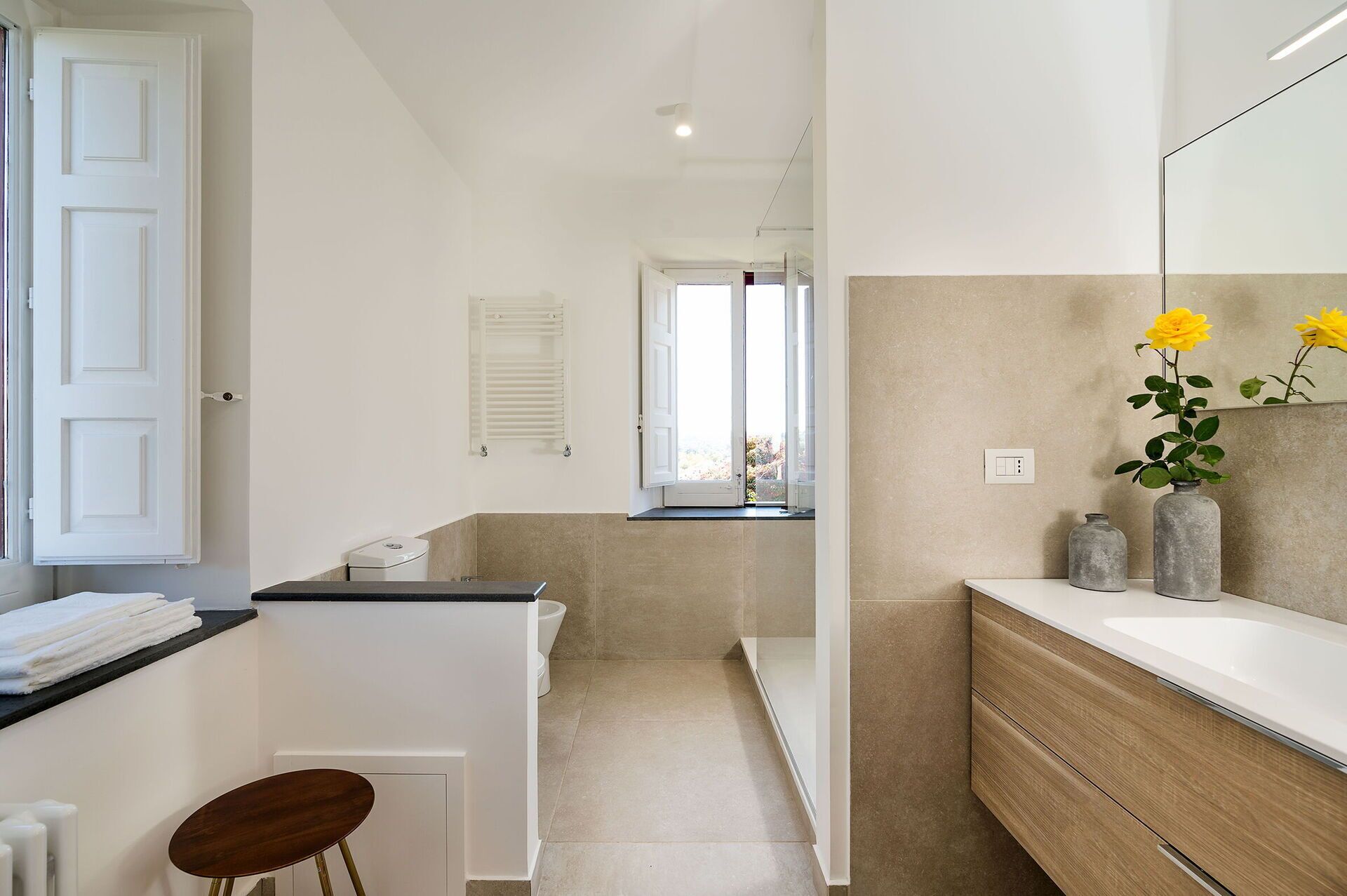 Ein modernes Badezimmer mit Dusche, Waschbecken und Toilette. An der Wand befinden sich ein Handtuchhalter und ein Spiegel.