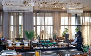 A hotel lobby with large windows, a buffet area, and modern chandeliers. - Fasq Hôtel Nouakchott (Nouakchott)