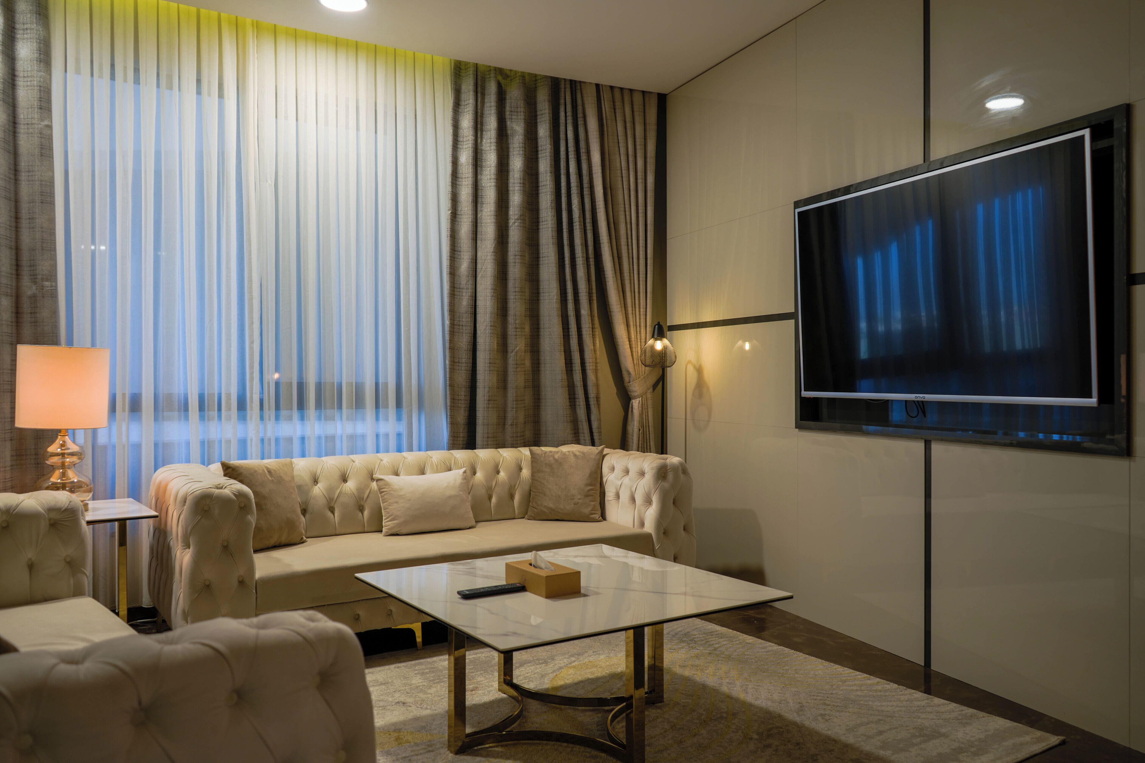 A modern living room with a sofa, a coffee table, a flat-screen TV, and a lamp.