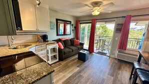 A modern kitchen with granite countertops, a built-in sink, and a dining area with a table and chairs. - Seas the Day! Beach & Sun, with Bikes & Chairs (Hilton Head Island)
