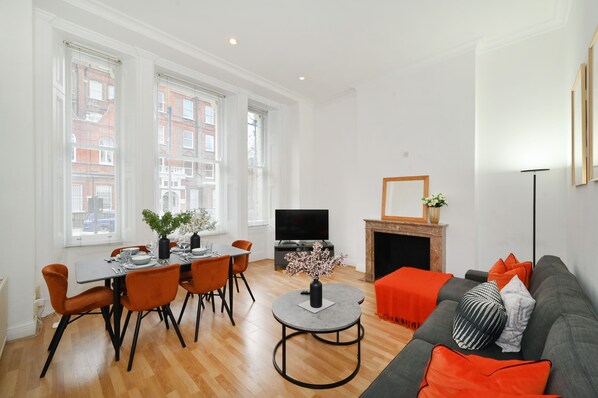 A modern living room with a dining area, a fireplace, and a television. - London Choice-Gloucester Road-Kensington (London)