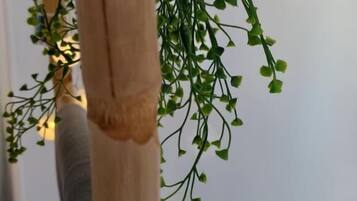 A wooden pillar with a textured surface and a hanging green plant with small leaves.