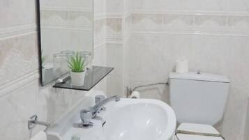 Un baño con lavamanos, espejo y retrete blancos.