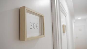 A framed number '306' on a white wall in a hallway.