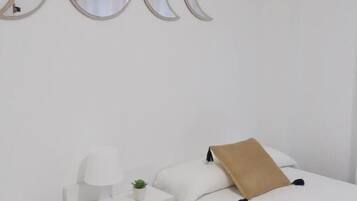 Un dormitorio con una cama, una mesita de noche y tres espejos fijados a la pared.