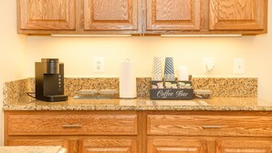 Una cucina con mobili in legno, una macchina da caffè, un dispenser di carta assorbente e un angolo caffetteria.