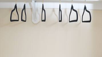 A white closet with black hangers and a rolled-up towel on the shelf.