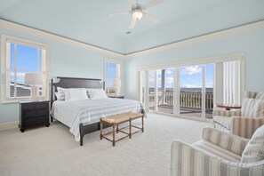 A bedroom with a bed, a nightstand, a chair, a balcony with a view, and a ceiling fan. - Luxury Oceanfront Retreat | 6 Ensuite Bedrooms | Sleeps 14 | Golf Cart Included | Steps to Beach Club (Fripp Island)