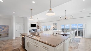 A spacious kitchen with a large island, white cabinetry, and a view to the outside. - Luxury Oceanfront Retreat | 6 Ensuite Bedrooms | Sleeps 14 | Golf Cart Included | Steps to Beach Club (Fripp Island)