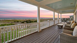 A covered porch with wicker furniture and a view of the beach at sunset. - Luxury Oceanfront Retreat | 6 Ensuite Bedrooms | Sleeps 14 | Golf Cart Included | Steps to Beach Club (Fripp Island)