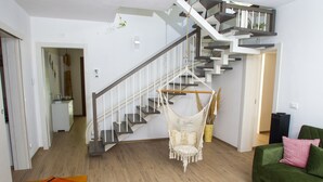 A modern living room with a staircase, a green sofa, and a hanging chair. - Modern Villa with heated jacuzzi,sauna,panoramic view,close to Tuscany (Pergoloso)