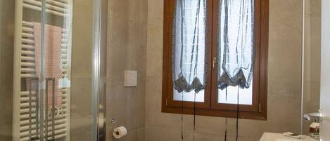 A bathroom with a glass shower enclosure, a toilet, a bidet, and a sink.