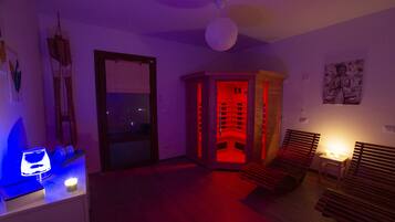 Una habitación con un banco de madera, una mesita con una lámpara y una esquina iluminada con luz roja.