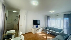 Relax in this stylish living room with a flat-screen TV, sofa, and dining area.
