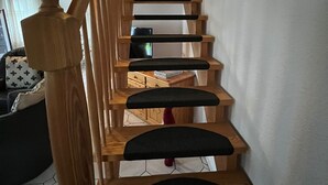 Un escalier en bois avec des marches recouvertes d’un rembourrage noir et une main courante en bois.