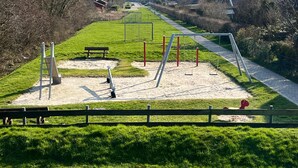 Une aire de jeux avec des balançoires, un toboggan et un banc.
