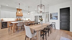 Una cocina moderna con armarios blancos, una mesa de comedor de madera y una puerta negra.