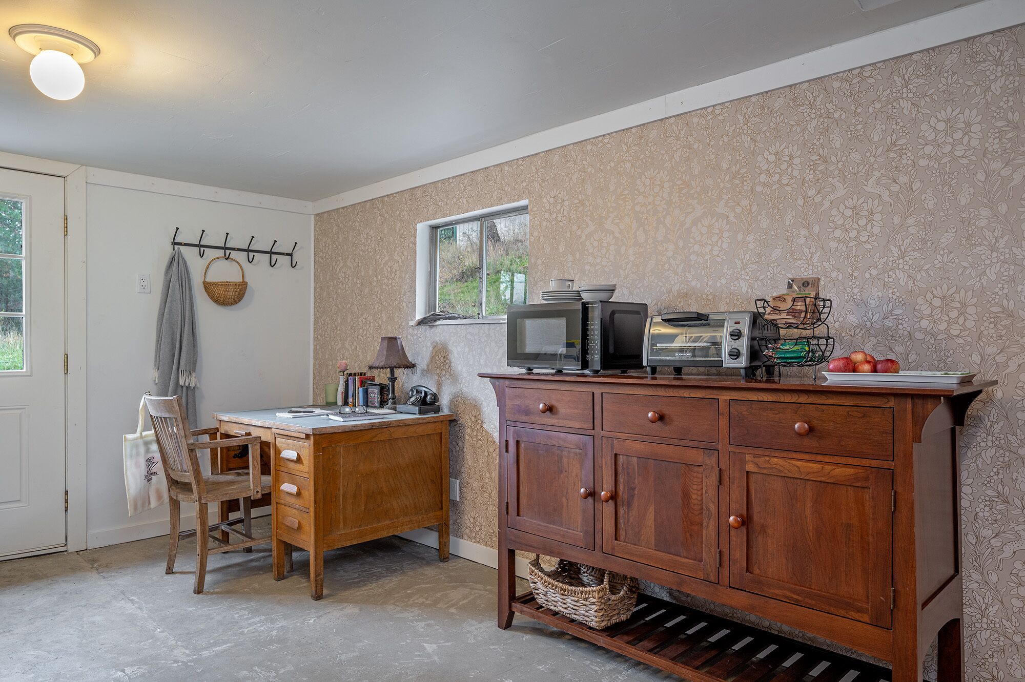 A kitchen with a wooden cabinet, a microwave, a toaster, and a window.