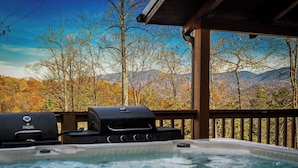 Un jacuzzi con vista a montañas y árboles otoñales.