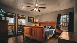 Un dormitorio con una cama de madera, un ventilador de techo y ventanas amplias.