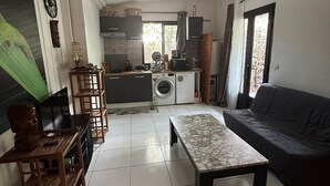 Una sala de estar con sofá, mesa de centro, televisor y comedor con sillas.