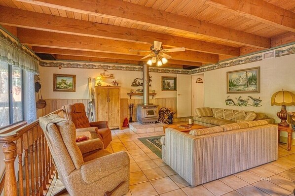 A cozy living room with a fireplace, wooden ceiling, and a large window. - A-Frame Cabin in The Sequoias (Wofford Heights)