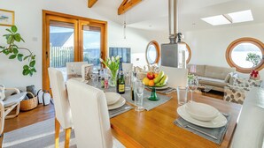 A dining area with a wooden table set for four, surrounded by white chairs. A large window provides a view of the outdoors. - 2 bedroom accommodation in Kilcreggan, near Helensburgh (Kilcreggan, near Helensburgh)
