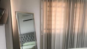 Une chambre à coucher avec un lit, un grand miroir et une armoire.