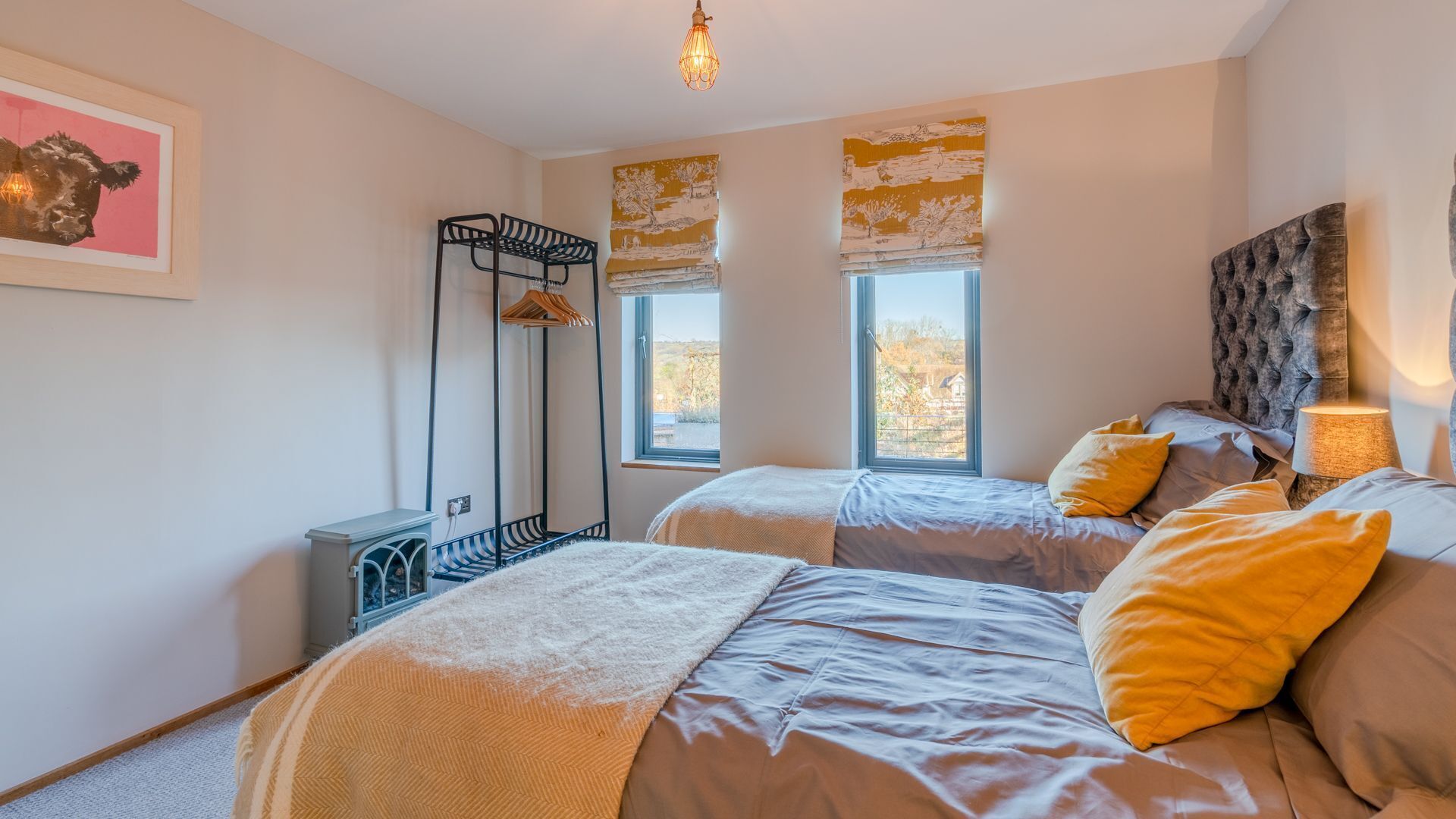 Quarto com duas camas, um radiador, uma janela com vista e uma luminária.