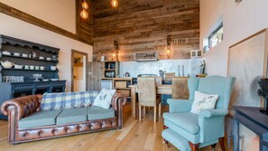 Cozy living space with a rustic aesthetic, featuring a wooden ceiling, leather sofa, and dining table.