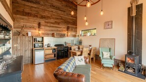 Cozy living space with a central kitchen, leather sofa, dining table, and fireplace.
