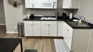 A modern kitchen with white cabinets, a black countertop, and a stainless steel sink. - Madison’s Place UNIT B (Peoria)