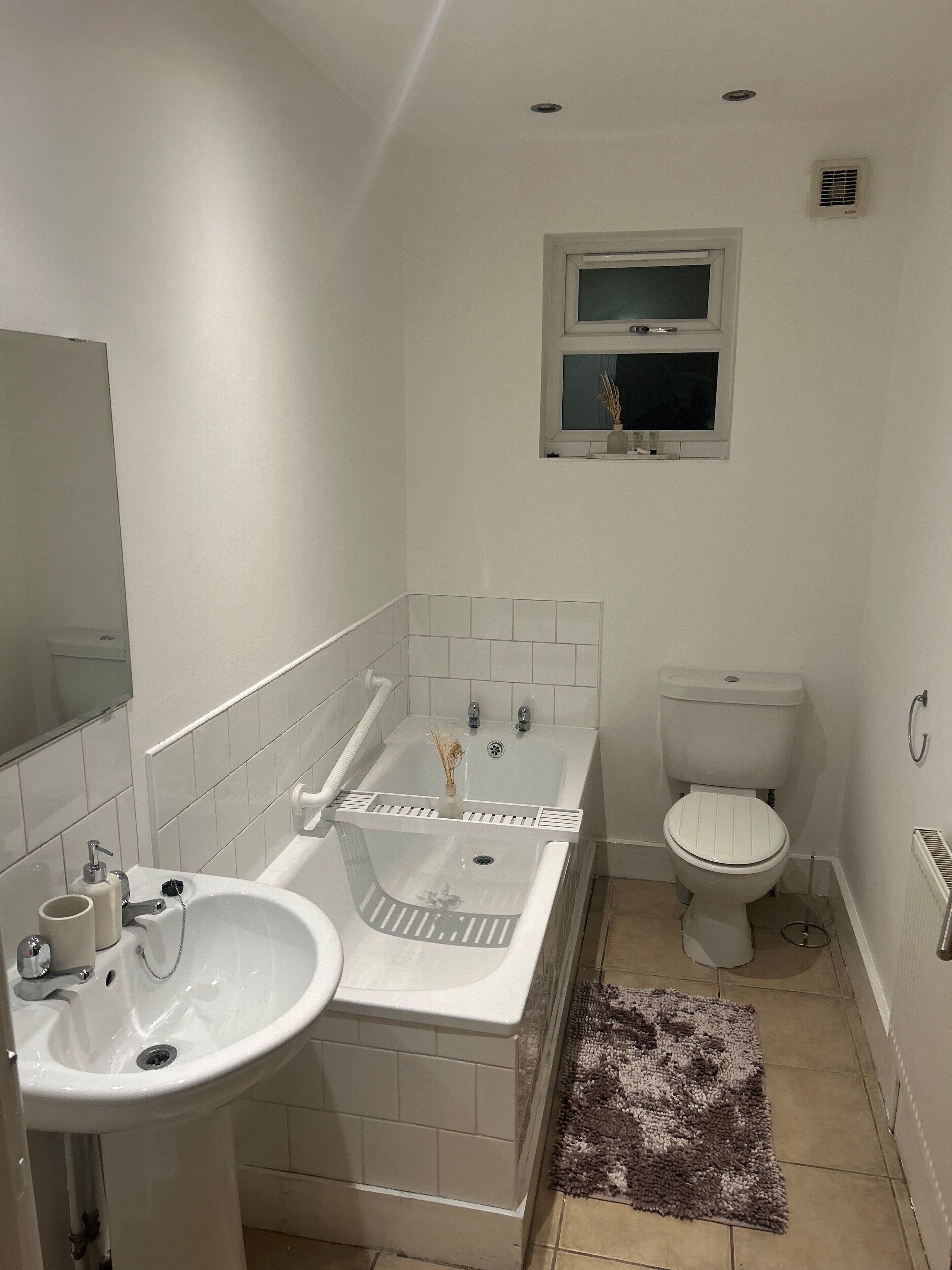 Ein Badezimmer mit Waschbecken, Badewanne, Toilette und einem Fenster über der Toilette.