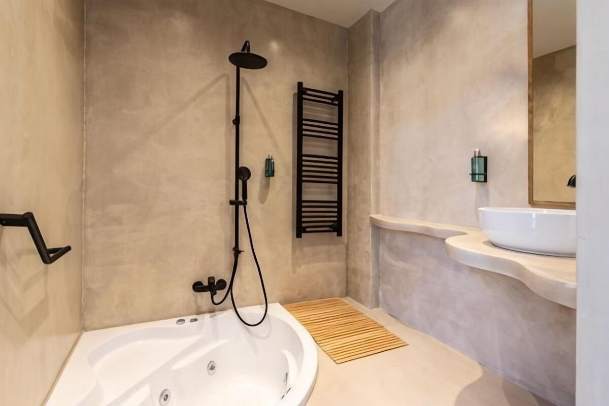 Un baño con bañera, ducha, toallero y lavabo.