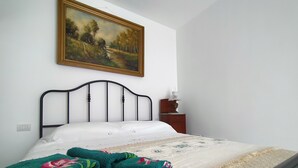 A bedroom with a bed, a nightstand, a lamp, and a painting on the wall. - Charming retreat near Polignano | Private parking + electric car charging station (Puglia)