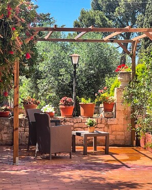 Une terrasse extérieure aménagée avec des meubles en osier, une table et des plantes en pot.
