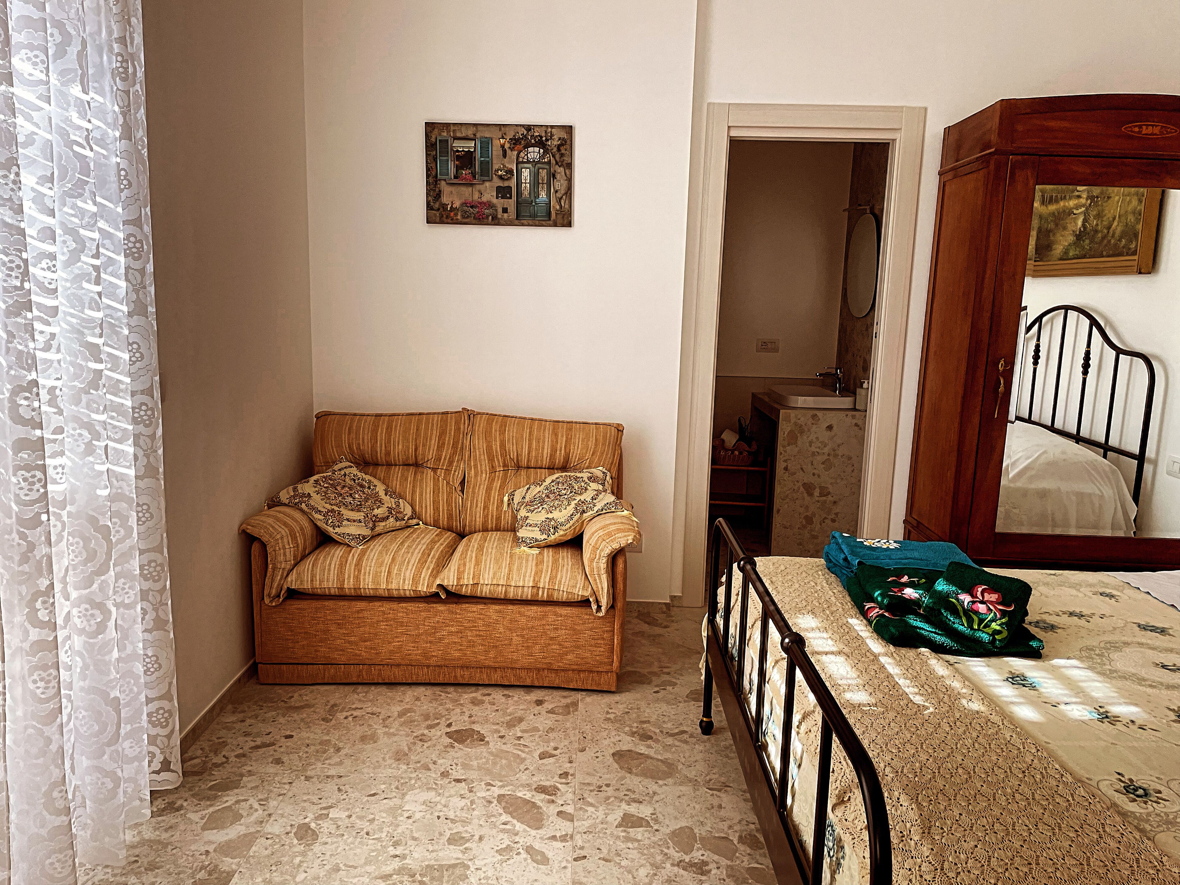 Ein Zimmer mit einer Couch, einem Bett, einem kleinen Tisch und einem Spiegel.