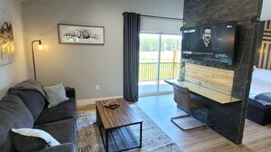 A modern living room with a sofa, coffee table, and a flat-screen TV mounted on a black wall. - Mountain Escape With Fireplace (Show Low)
