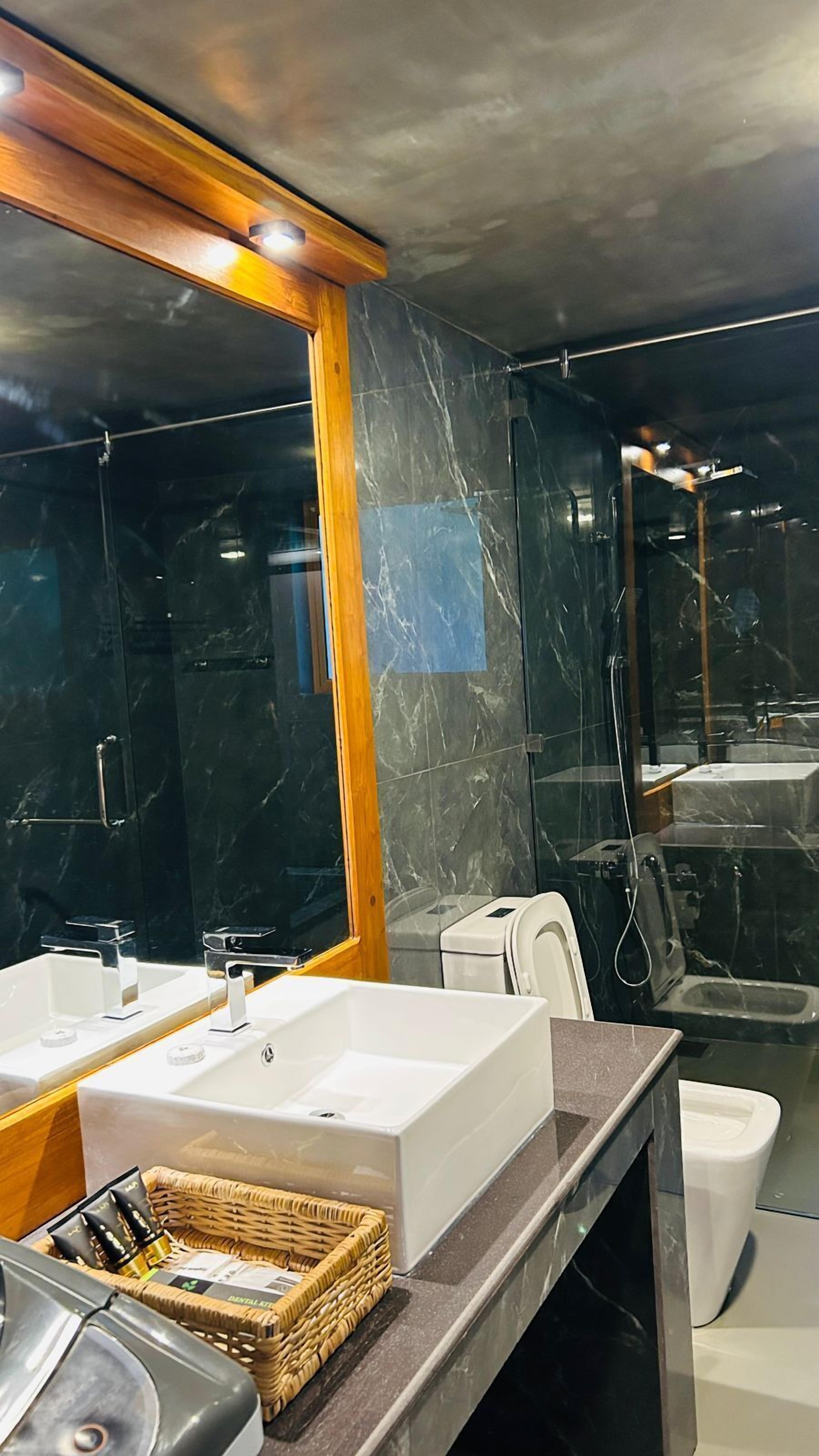 A modern bathroom with two sinks, a shower, and a toilet.
