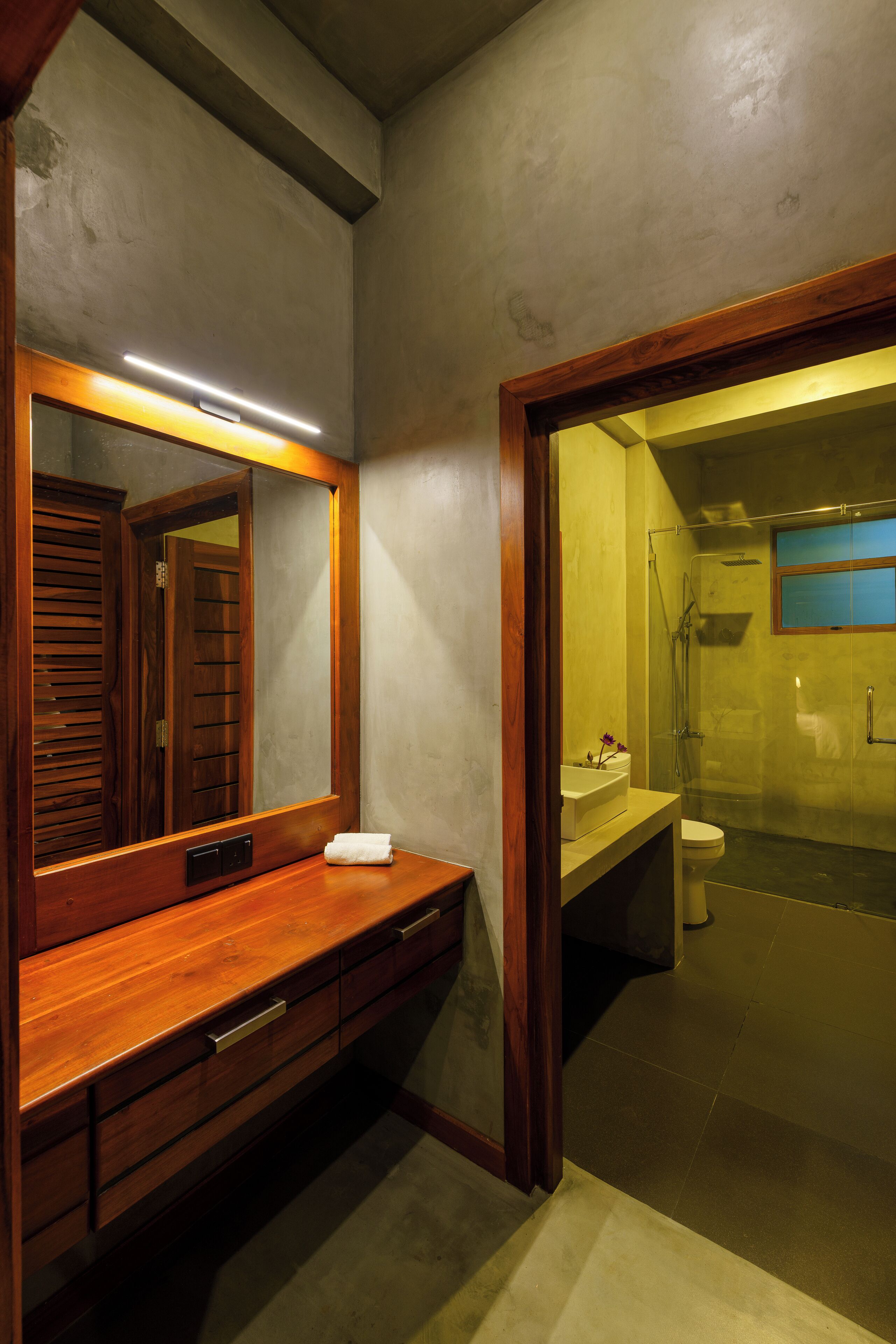A bathroom with a wooden vanity, a large mirror, and a glass-enclosed shower area.