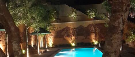 Una piscina rodeada de árboles y un edificio con luces.