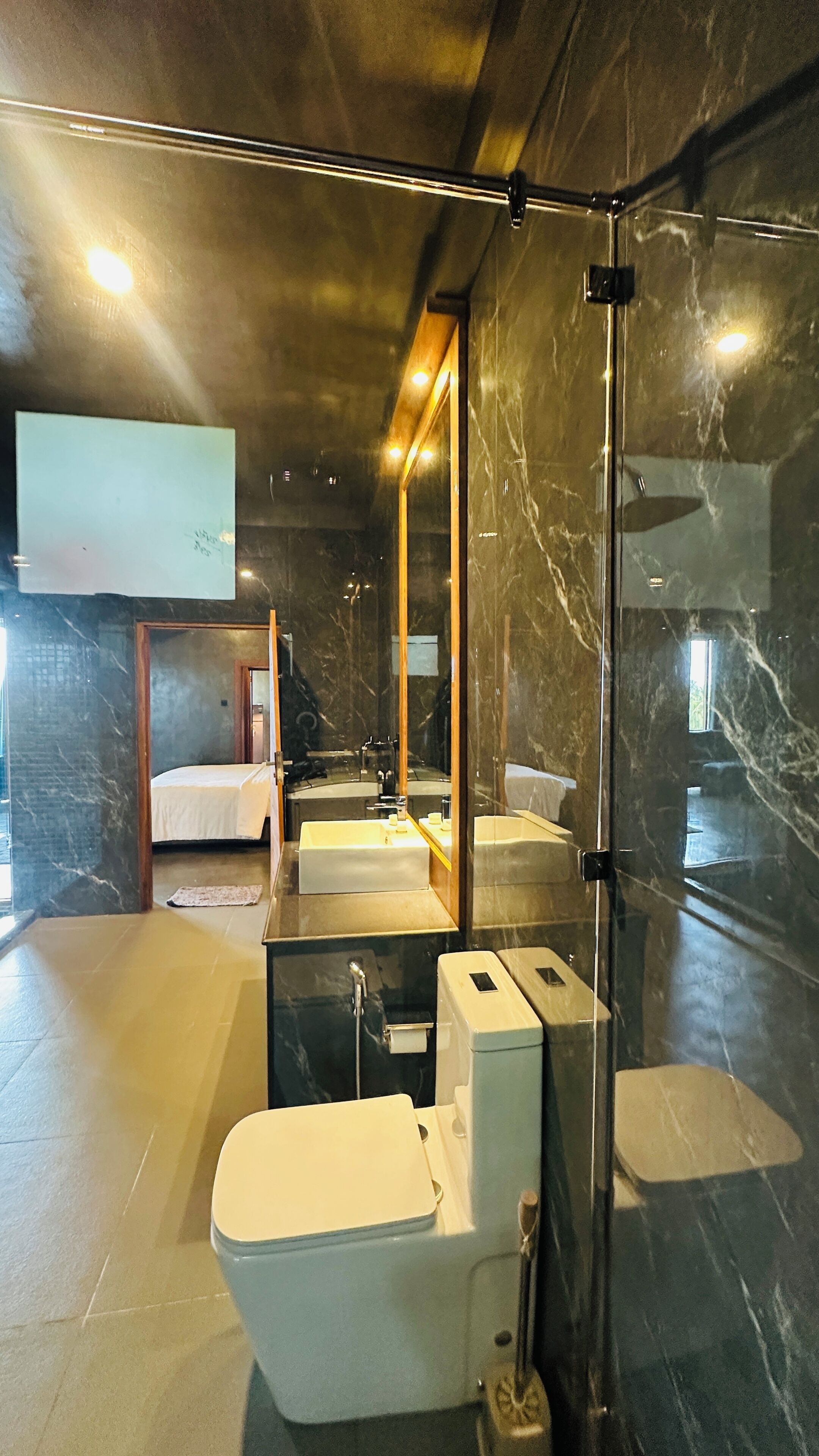 A modern bathroom with a glass shower enclosure, a large mirror, a bathtub, and a toilet.