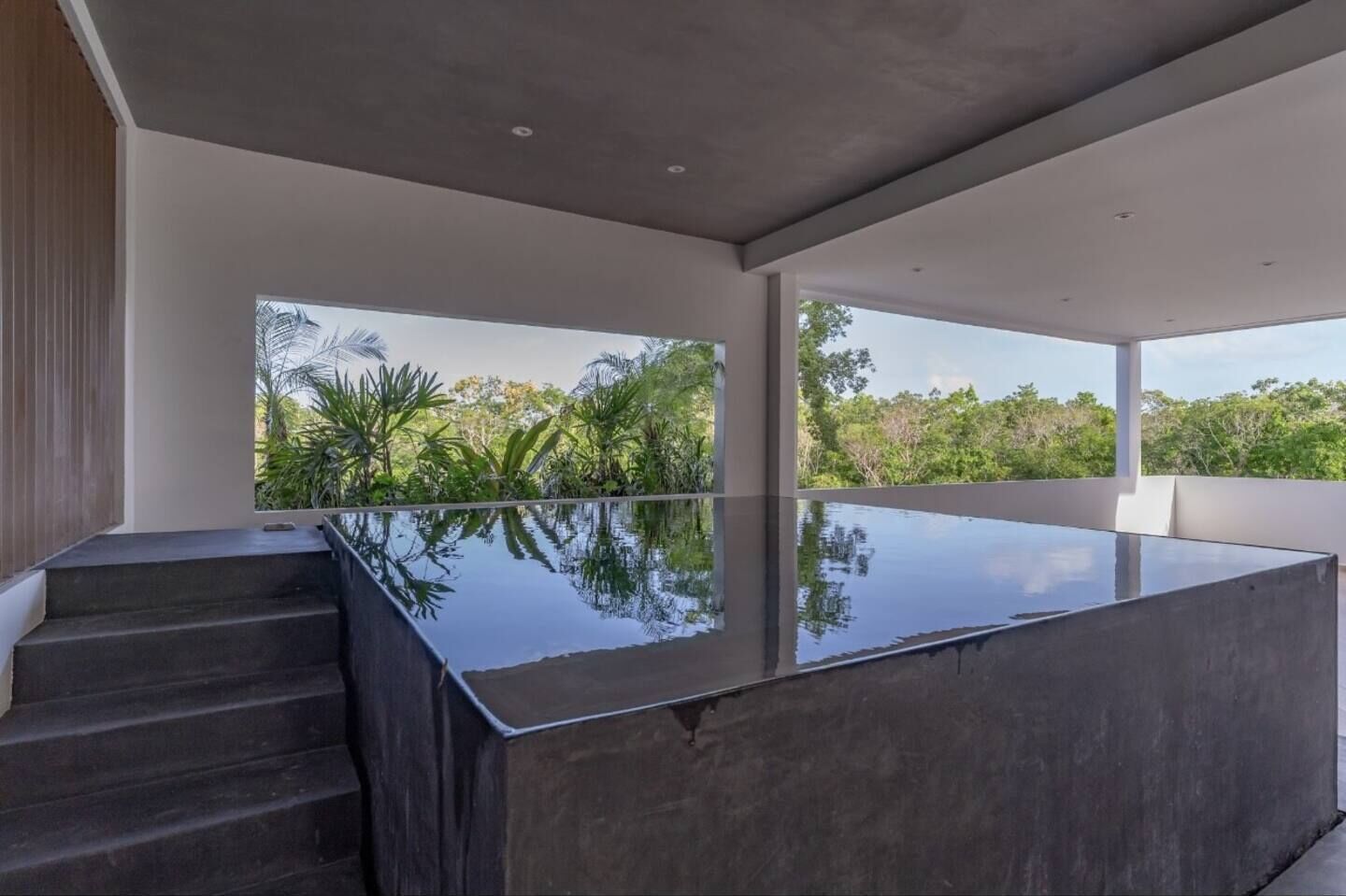 A modern interior with a large glass pool reflecting the surrounding greenery.