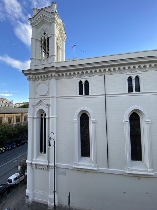 A white building with a bell tower, arched windows, and a street view. - Domus romae esquilini (Roma)