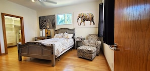 Cozy retreat with a central bed, nightstand, and chair, surrounded by abstract artwork.