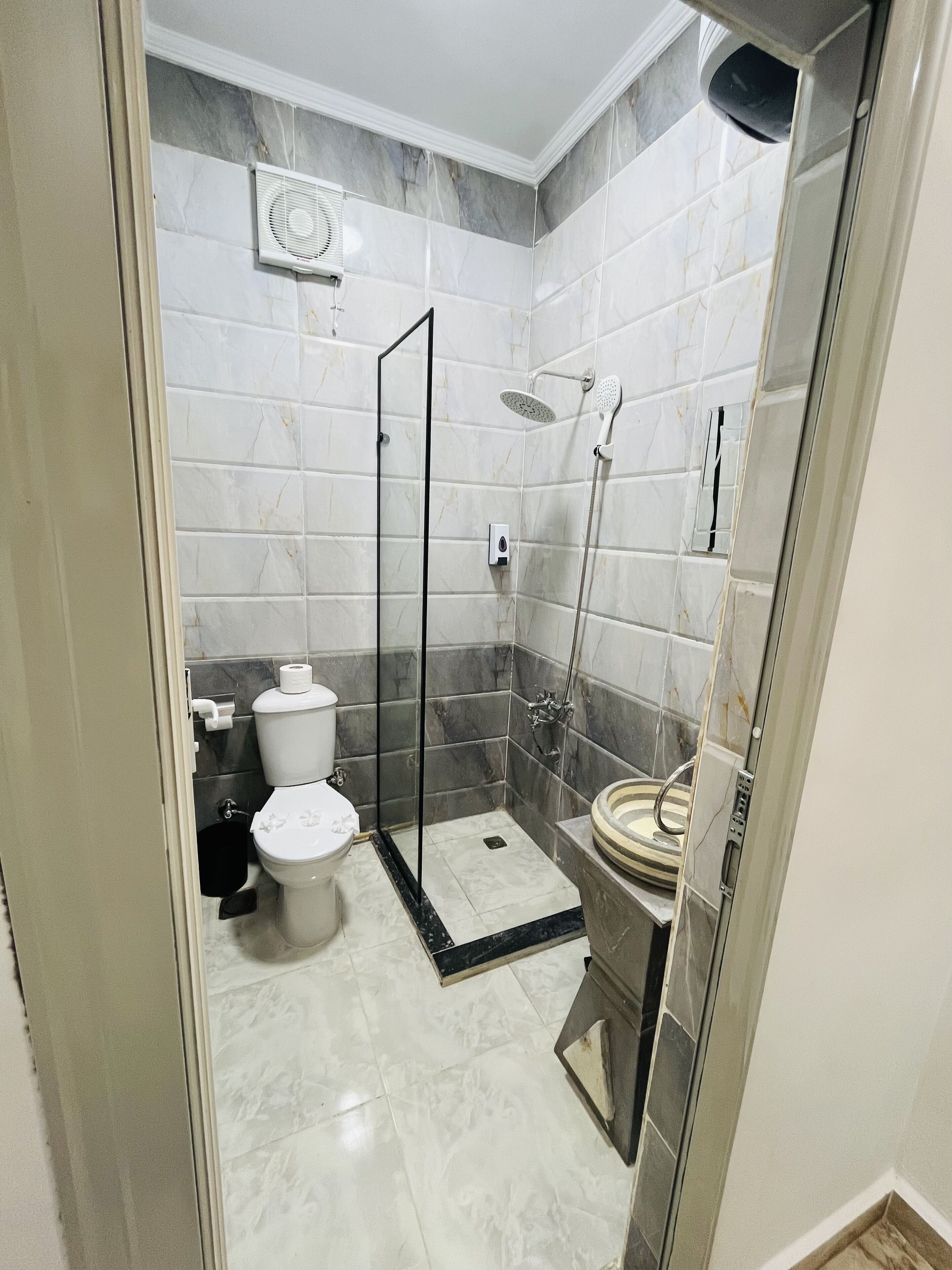 A modern bathroom with a glass-enclosed shower, a toilet, and a bidet.