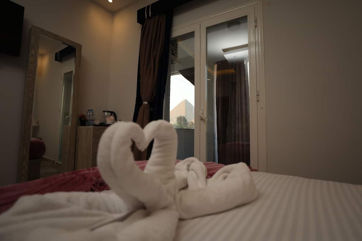 Et hotelværelse med seng, spejl, kommode og et vindue med gardiner.