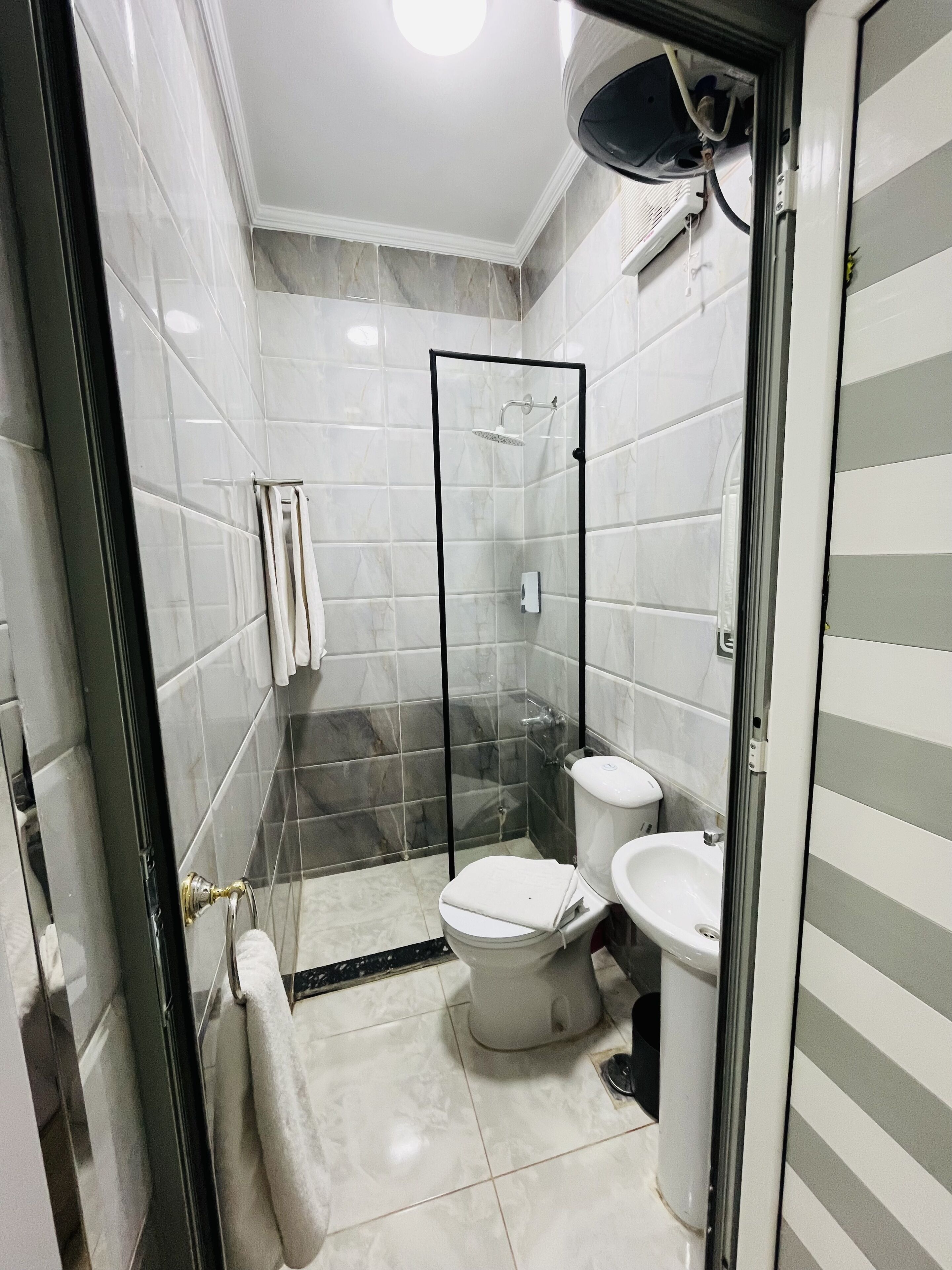 A modern bathroom with a glass-enclosed shower, a toilet, and a sink.