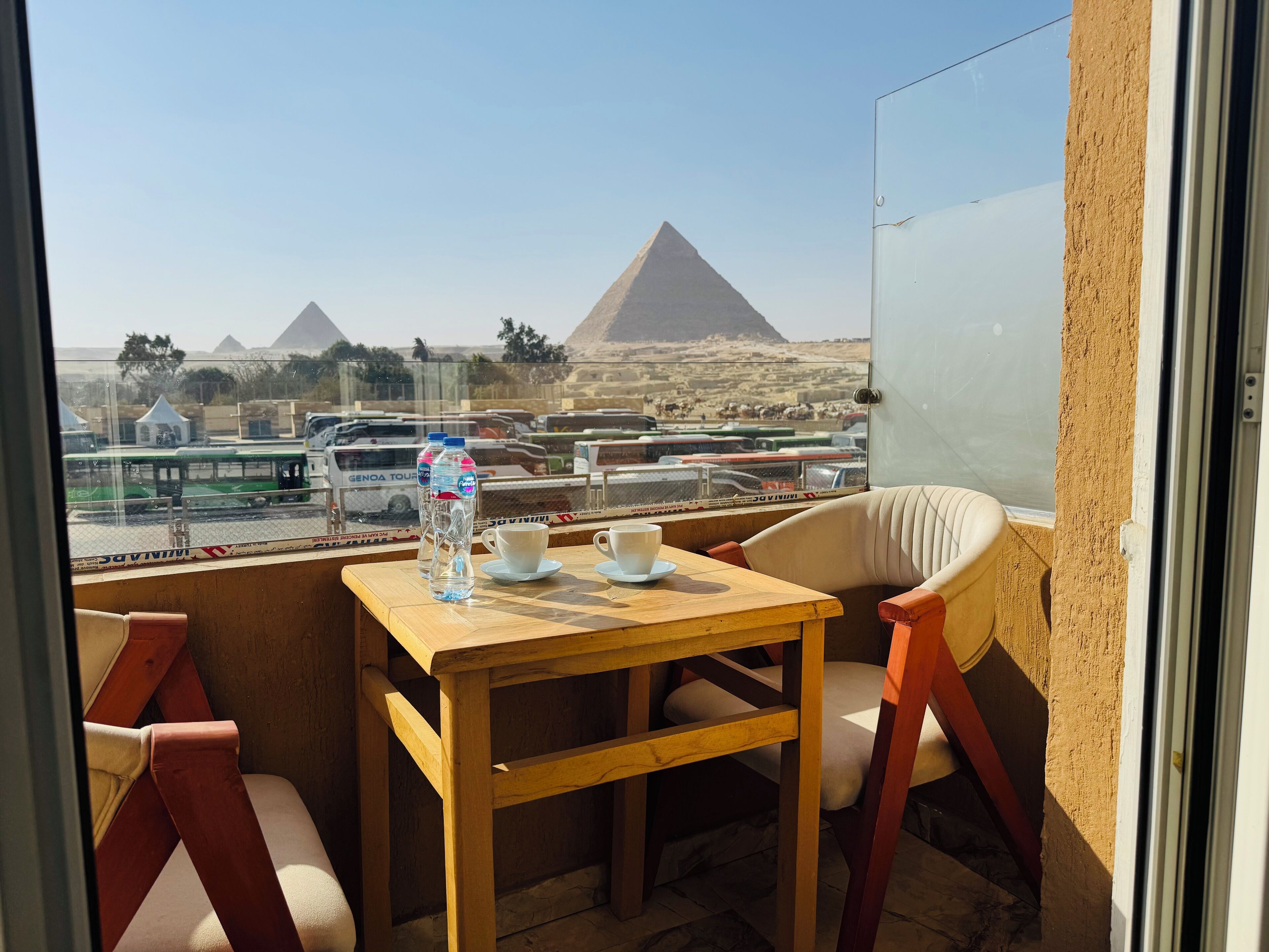 A balcony with a table, two chairs, and a view of pyramids.